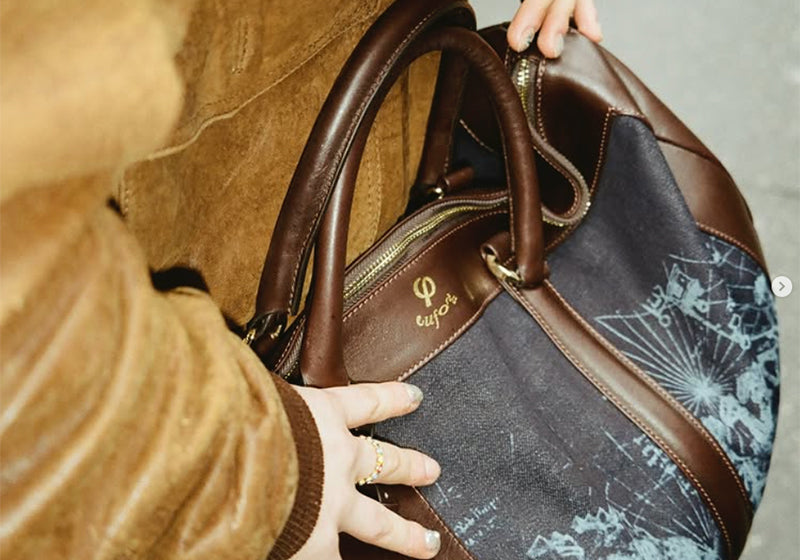 Person carrying the Euforia Weekend Bag in navy denim and brown leather