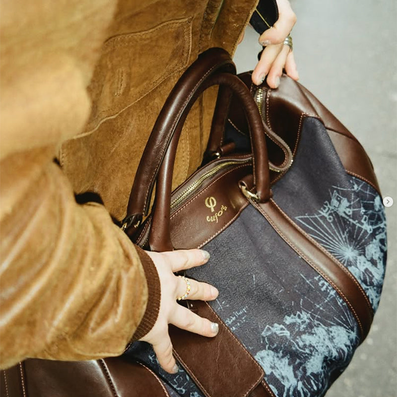 Person carrying the Euforia Weekend Bag in navy denim and brown leather