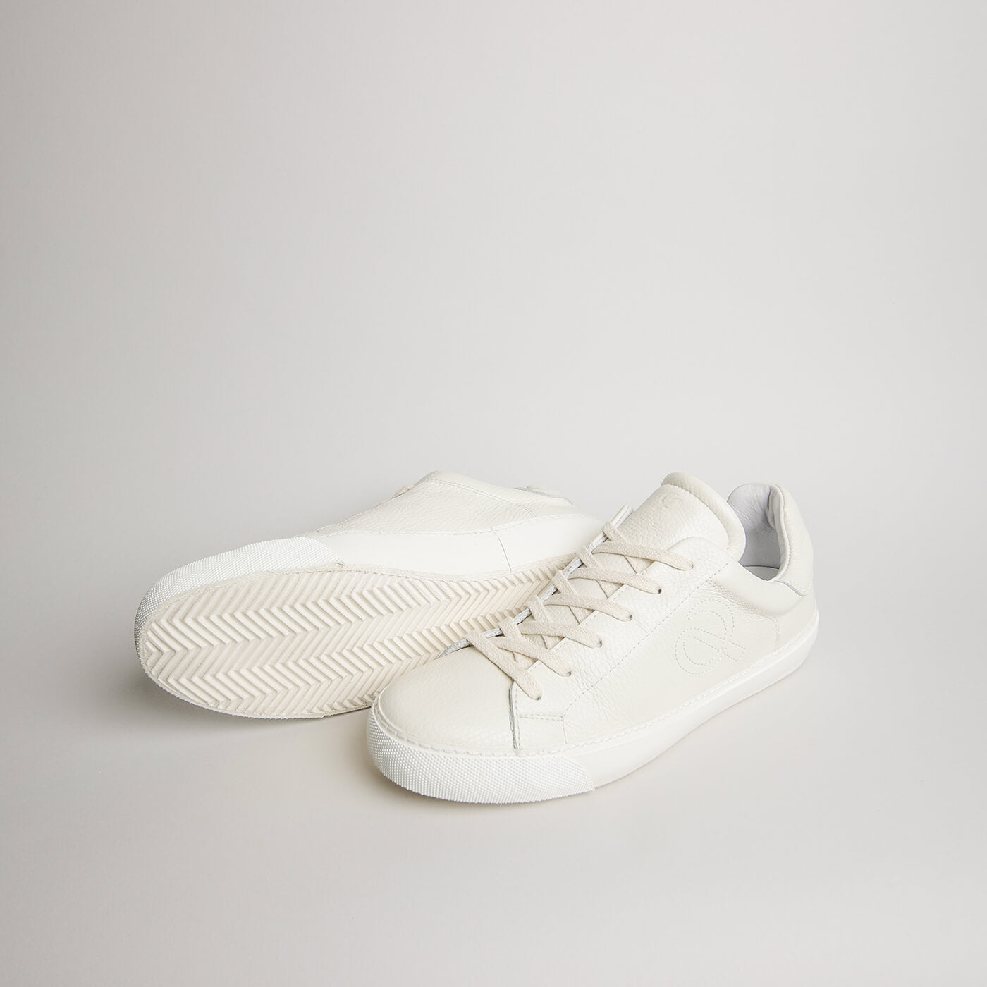 Angled pair of men’s white tumbled leather Milano sneakers with herringbone outsoles