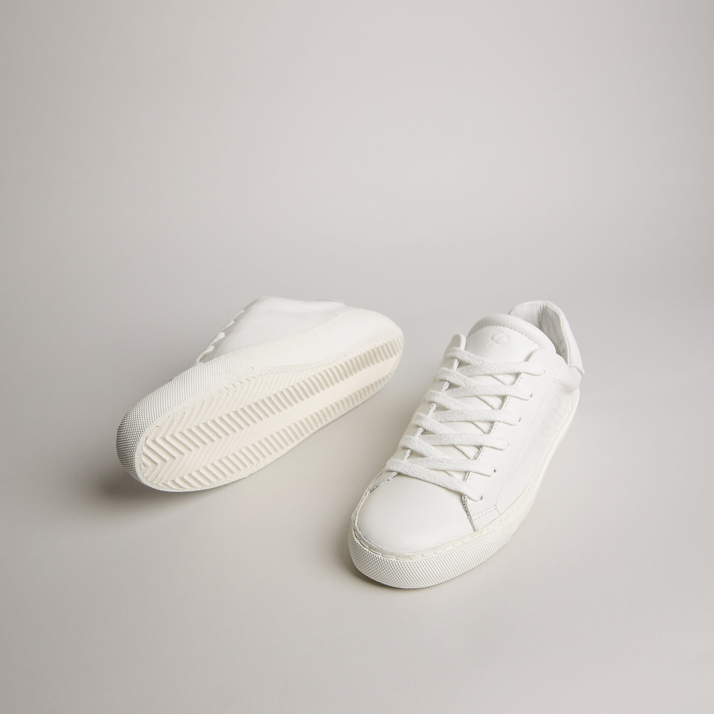 Angled pair of women’s white goat leather Milano sneakers with herringbone outsoles