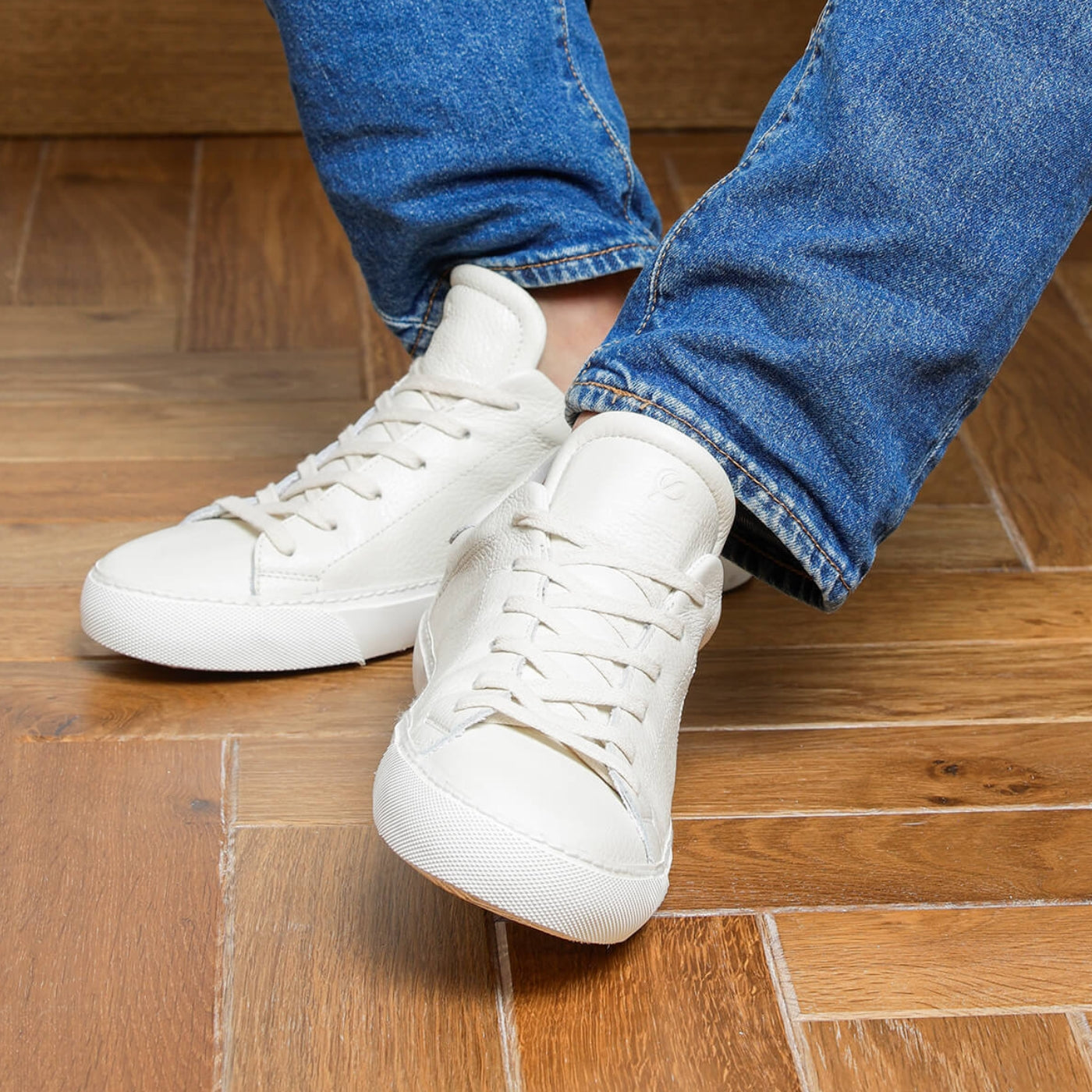 Man wearing white tumbled leather Milano sneakers while seated