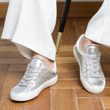 Woman wearing silver goat leather Milano sneakers, front view