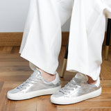Woman wearing silver goat leather Milano sneakers, side view