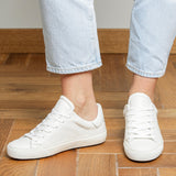 Woman wearing white goat leather Milano sneakers, front view