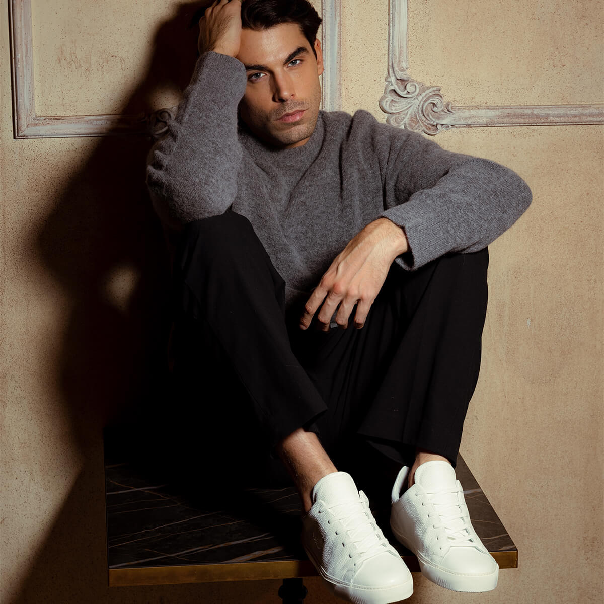 Man seated in white Euforia sneakers in a Milan interior