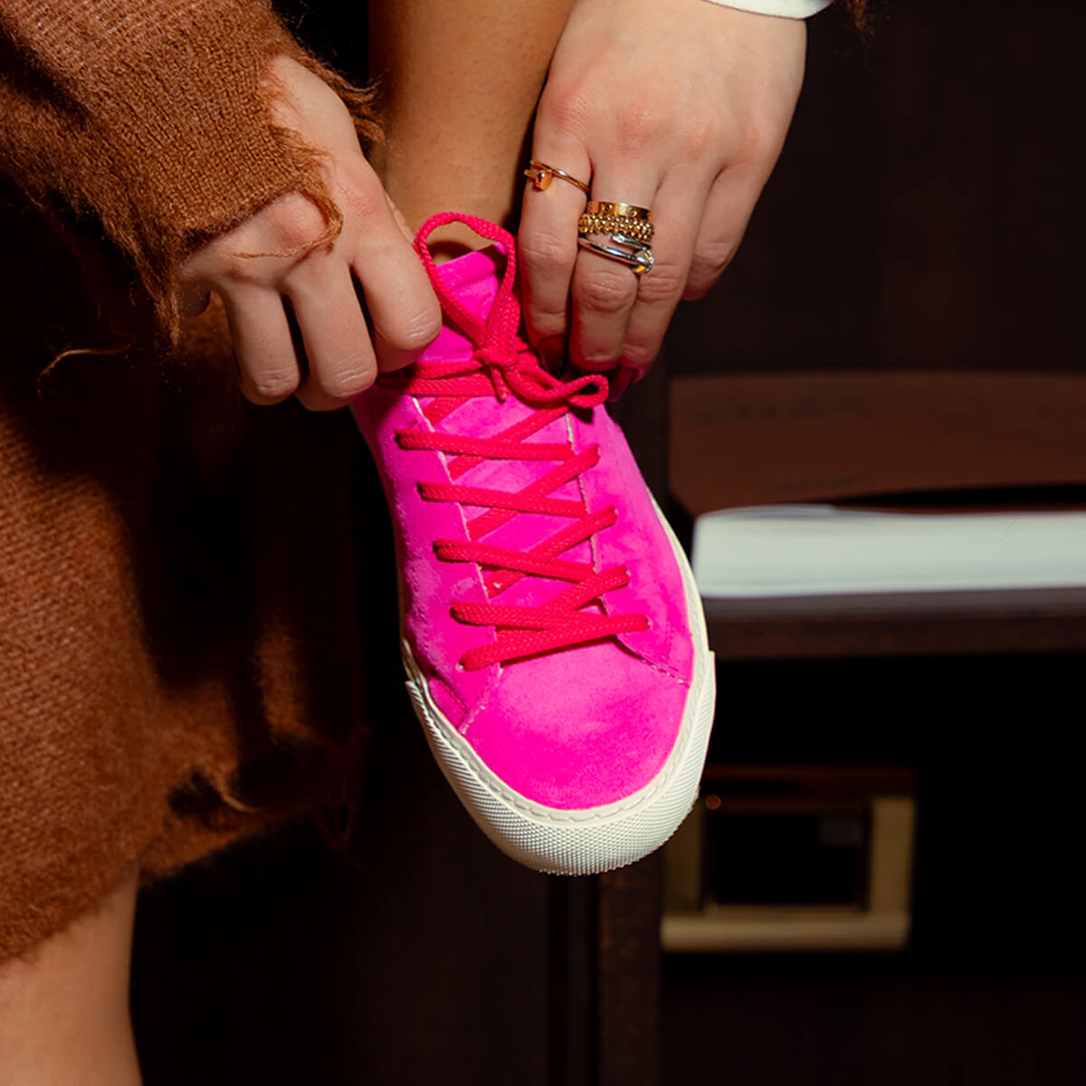 Close-up of a woman lacing a vivid pink Euforia sneaker