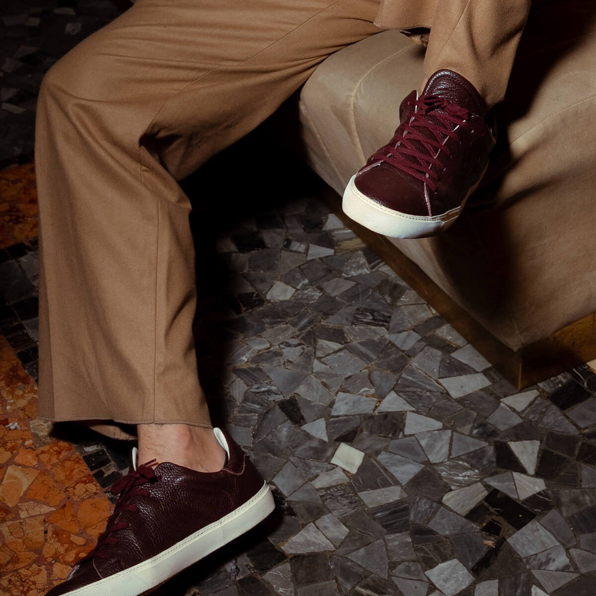 Model wearing burgundy Euforia sneakers on a mosaic floor
