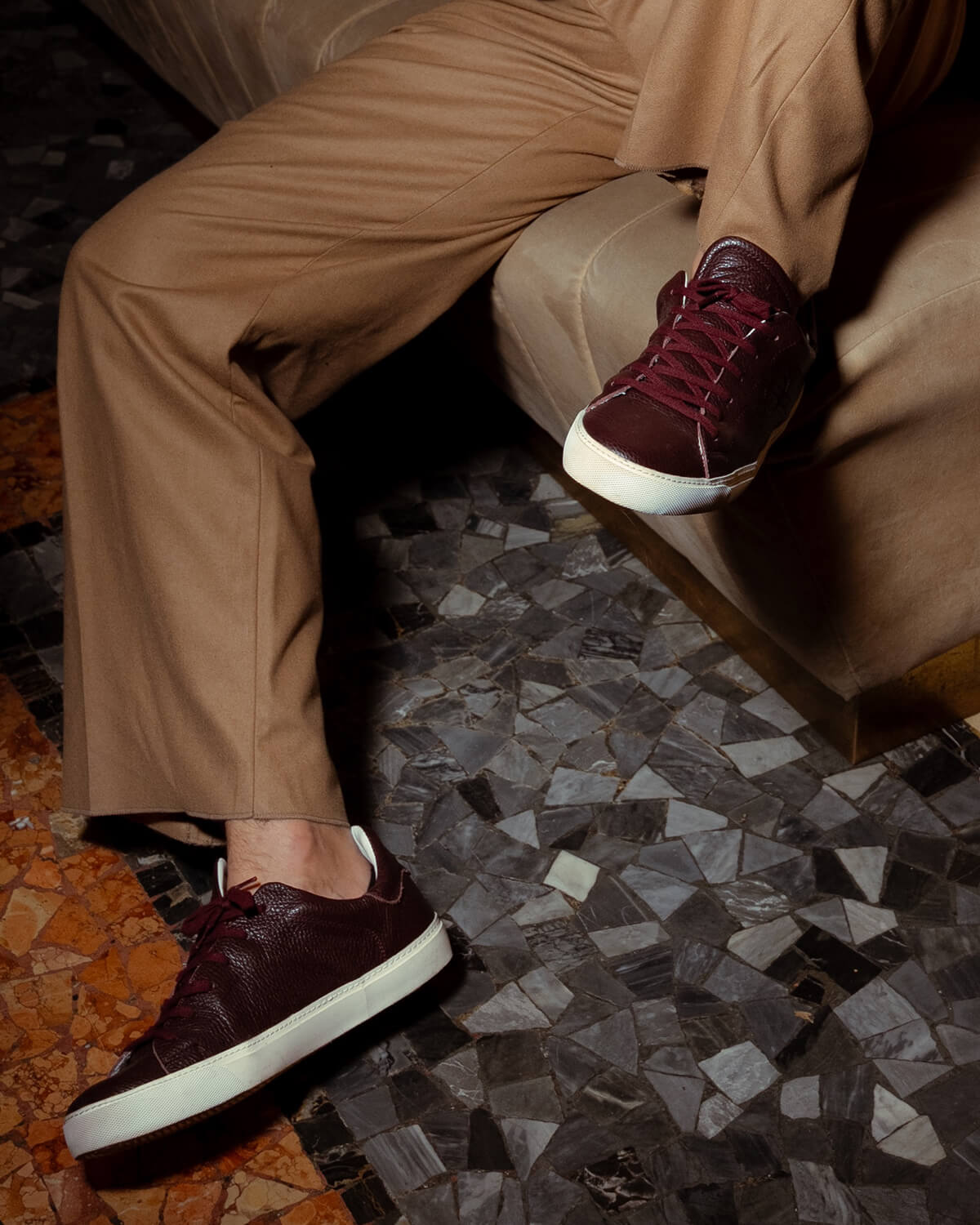 Model wearing burgundy Euforia sneakers on a mosaic floor